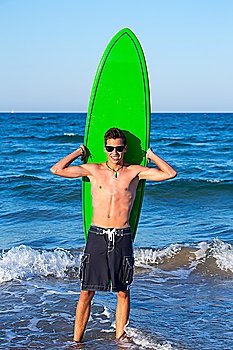 Boy handsome teen surfer holding surfboard in the blue beach
