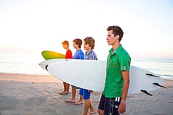 Surfer teenager boys group walking at beach shore on sunshine or sunset