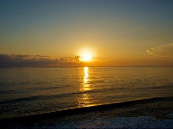 Ocean sunset. Sun over horizon reflecting on water surface.