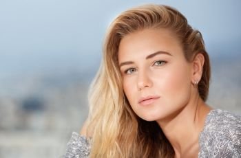 Closeup portrait of beautiful blond woman outdoors over soft focus background, healthy natural beauty
