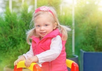 Portrait of cute little blond girl having fun on playground in warm sunny day, adorable kid playing outdoors, happy carefree childhood