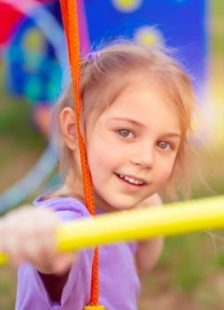 Closeup portrait of a cute little girl on the swing on playground, happy child with pleasure spending time outdoors, baby girl enjoying sport, happy carefree childhood
. Little girl on playground