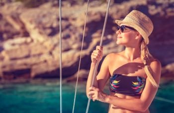 Beautiful happy girl tanning on the deck of sailboat, enjoying warm bright sun light, interesting adventure in the sea, beach summer vacation
. Happy girl on summer vacation