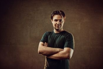 Male positive portrait. On dark stone wall background. Warm colors.