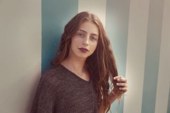 Brunette teen girl portrait in a summer beach blue stripes wall filtered image