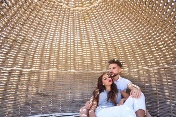 Tourist couple relaxed inside a beach parasol in summer vacation