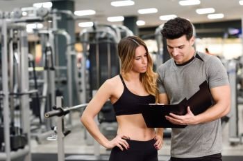 Personal trainer and client looking at her progress at the gym. Athletic man and woman wearing sportswear.