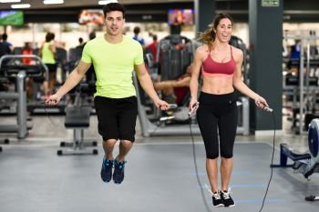 Handsome man and beautiful sporty woman workout with jumping rope in crossfit gym