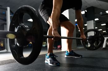 Closeup of weightlift workout at the gym with barbell. Man wearing sportswear clothes.