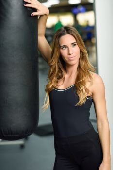 Female personal trainer with punching bag in a gym. Woman wearing sportswear clothes.