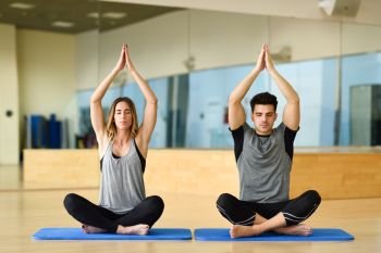Young woman and man practicing yoga indoors. Two people doing exercises.