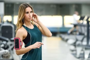 Young woman using smartphone standing in the gym before the training.
