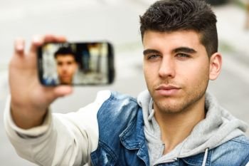 Handsome young man selfie in urban background with a smartphone wearing casual clothes