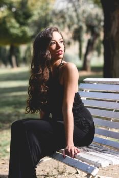 Portrait of pretty girl with long hair wearing black clothes in a park