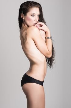 Half naked brunette woman wearing panties with very long curly hair on white background. Studio shot