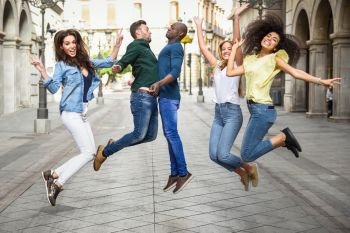 Multi-ethnic group of young people having fun together outdoors in urban background. group of people jumping together
