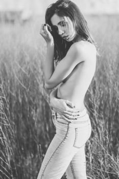 Fashion photograph of young sensual woman in jeans, in nature