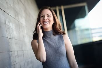 Beautiful young woman talking with a smartphone in an office building