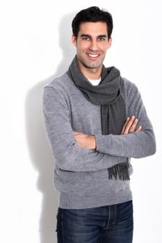 Handsome man wearing winter clothes smiling on white background. Young male with swater and scarf looking at camera. Studio shot