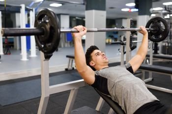 Young man bodybuilder doing weight lifting in gym. Attractive man wearing sportswear