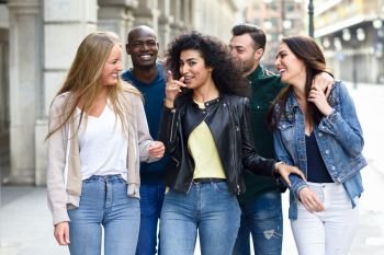 Multi-ethnic group of young people having fun together outdoors in urban background. group of people walking together pointing with the finger