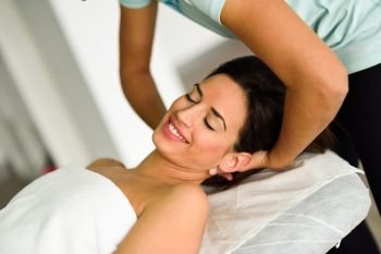 Young caucasian smiling woman receiving a head massage in a spa center with eyes closed. Female patient is receiving treatment by professional therapist.