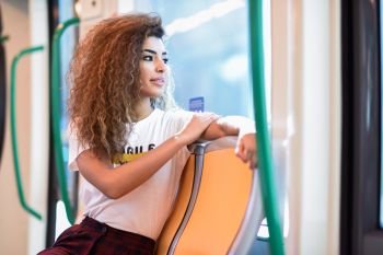 Arabic woman inside subway train. Arab girl in casual clothes near a window.
