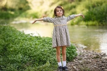 Little beautiful girl in nature stream wearing beautiful dress