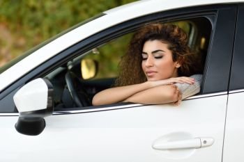 Beautiful young arabic woman inside a nice white car with eyes closed. Arab girl wearing casual clothes.