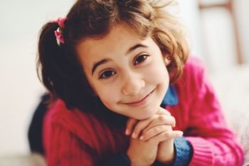 Adorable little girl with sweet smile lying down on bed. Close-up potrait.