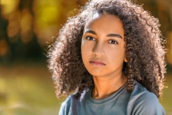Beautiful mixed race African American girl teenager female young woman outside in autumn or fall looking sad depressed or thoughtful