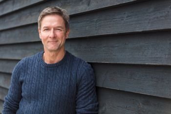 Portrait shot of an attractive, successful and happy middle aged man male smiling outside wearing a blue sweater. Happy Middle Aged Man Outside