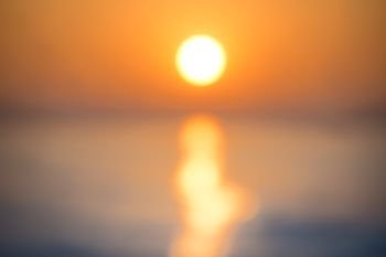 Blur abstract sunset over sea with sun, waves and shining light on the water- blurred background. Blur abstract sunset over sea