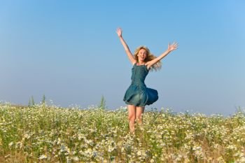 The happy young woman jumps in the field  of camomiles

