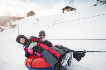 Mother and her son on a snow tube, at beauty winter day