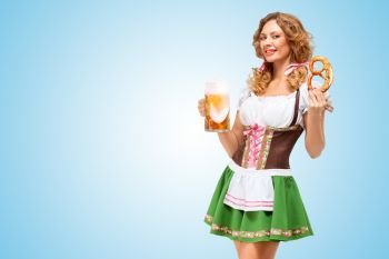 Young sexy Oktoberfest waitress wearing a traditional Bavarian dress dirndl offering a pretzel and beer mug on blue background.