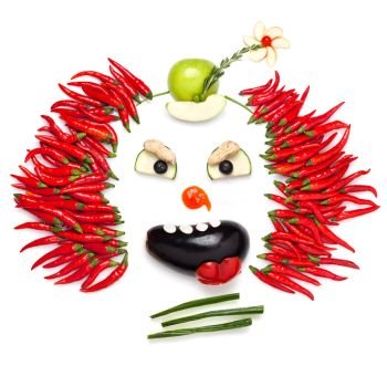 A creative food concept demonstrating a creepy halloween clown with the help of chilli pepper and other vegetables.