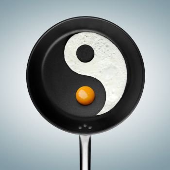 An yin-yan symbol made of fried egg in a pan.