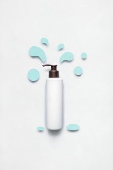 Creative concept photo of cosmetic bottle with splashing liquids made of paper on white background.