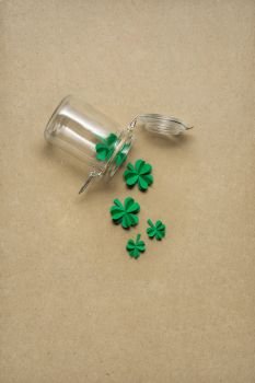 Creative St. Patricks Day concept photo of a bottle with shamrocks made of paper on brown background.