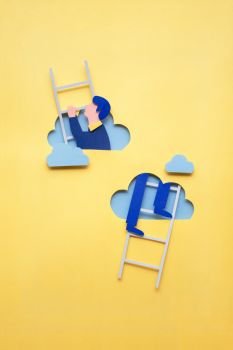 Creative concept photo of man climbing ladder made of paper on yellow background.