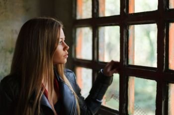 Pensive blonde woman next to a windows