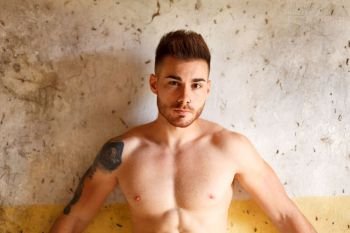 Attractive guy showing his muscles in a old house