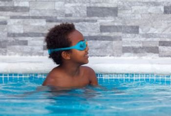 Little african child in the pool . Little african child with orange sleeve floats in the pool 