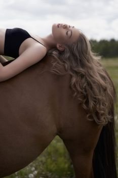 Outdoor art fashion photo of beautiful young lady with horse. 