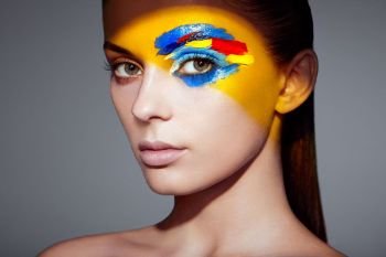 Fashion model woman with colored face painted. Beauty fashion art portrait of beautiful woman with colorful abstract makeup. Face painted paints. Multicolor design