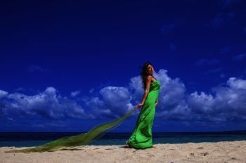Woman in dress on beach. Woman in green dress posing with fabric in tropical sea beach