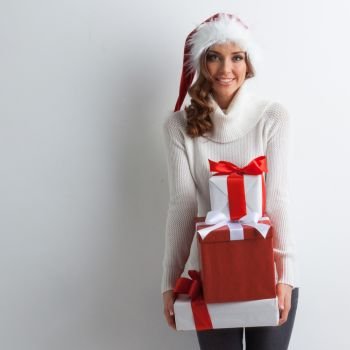 Woman with stack of gifts. Happy woman in Santa hat with stack of Christmas gifts