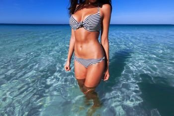 Woman in bikini. Woman with perfect body in bikini standing in blue sea