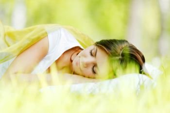 Beautiful young woman sleeping on grass outdoors